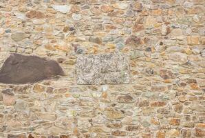 Close-up of a natural stone wall with rough texture and uneven stones, perfect for backgrounds. photo
