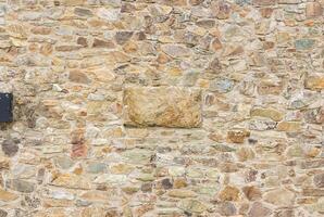 Close-up of a natural stone wall with rough texture and uneven stones, perfect for backgrounds. photo