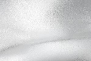 A close-up view of a frosted silver metallic texture with a subtle wave-like pattern, perfect for backgrounds or design elements. photo