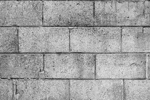Black and white image of rough concrete block wall texture with visible wear and marks. photo