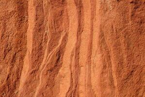 Close-up of red sandstone rock texture featuring natural wavy patterns and rough surface. photo