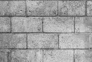 Black and white image of rough concrete block wall texture with visible wear and marks. photo