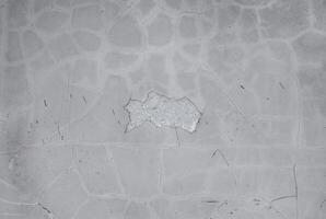 Textured concrete surface with visible cracks and faint scratches, offering a neutral and industrial background. photo