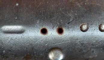 Close-up of a rough metallic surface featuring scratches, dents, and weathered texture, ideal for industrial backgrounds. photo