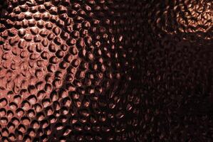 Abstract close-up of a copper-textured surface with circular patterns. photo
