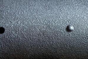 Close-up of dark metallic surface with rough texture, ideal for industrial design, backgrounds, and material projects. photo