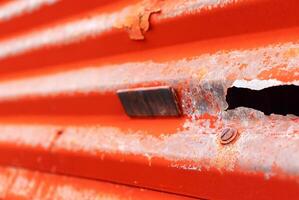 Close-up of rusty orange corrugated metal sheet with peeling paint and texture, ideal for industrial design projects. photo