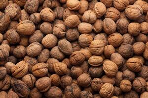 Close-up of a large pile of whole walnuts in their shells, showing a natural and organic texture. photo