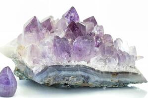 Close-up of a raw amethyst geode crystal with purple and clear quartz formations, isolated on a white background. photo