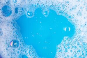 Close-up image of blue water with soap bubbles forming on the surface, perfect for cleaning, hygiene, and background projects. photo