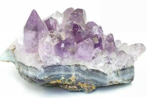 Close-up of a raw amethyst geode crystal with purple and clear quartz formations, isolated on a white background. photo