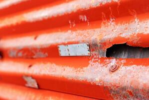 Close-up of rusty orange corrugated metal sheet with peeling paint and texture, ideal for industrial design projects. photo