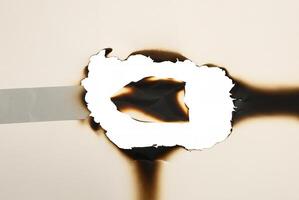 Paper with a burnt hole and charred edges, isolated on a white background, ideal for creative or design projects. photo