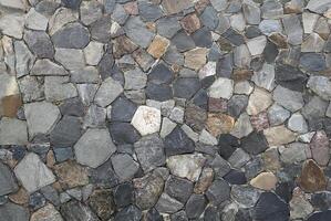 Close-up of a natural stone wall texture with various irregular stones in shades of gray, brown, and beige, perfect for backgrounds. photo