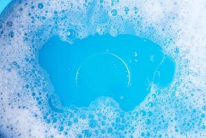 Close-up image of blue water with soap bubbles forming on the surface, perfect for cleaning, hygiene, and background projects. photo