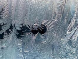 Close-up of intricate ice frost patterns on a glass window, creating a natural, cold, and textured winter background. photo