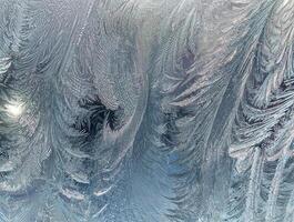 Close-up of intricate ice frost patterns on a glass window, creating a natural, cold, and textured winter background. photo