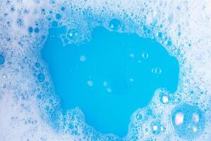 Close-up image of blue water with soap bubbles forming on the surface, perfect for cleaning, hygiene, and background projects. photo