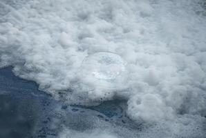 Close-up of white foam and bubbles floating on water surface, perfect for backgrounds, texture, or environmental concepts. photo