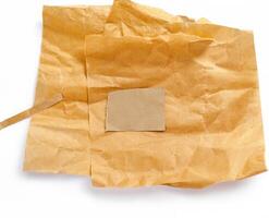 Crumpled brown paper sheets placed on a white background, perfect for textures, crafts, or packaging design elements photo