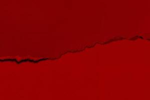 Close-up of a torn red paper texture with a rough edge, perfect for use as an abstract background or design element. photo