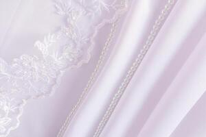 Chic wedding backdrop for design with waves of white satin fabric, pearl beads and part of a lace veil. A copy of the space. photo