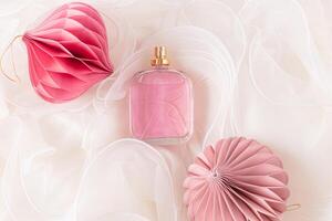 A beautiful bottle of cosmetic spray or perfume on a beige wavy fabric background with New Year's paper eco balls with honeycombs. top view. photo