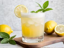 Close up side view of lemonade juice in glass on wooden cutting board adorned with lemon sliced and mint leaf decorated by lemon fruit against white background photo
