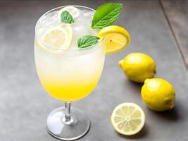 Close up high angle view of lemonade juice in wine glass on wooden table adorned with lemon sliced and mint leaf decorated two lemon fruit and one sliced lemon photo