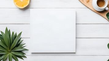 Top view blank space white square paper mock up adorned by coffee orange and little plant on white table for creative design photo