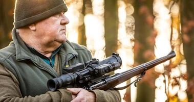 Portrait of hunter or ranger with a hunting gun and hunting form to hunt in an autumn forest, hunting concept photo