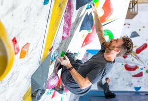 Young climber climbing on the boulder wall indoor, rear view, concept of extreme sports and bouldering photo