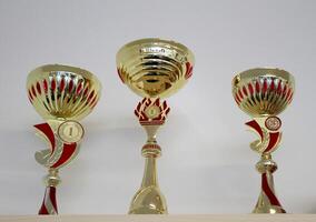 Golden sports cups for winning competitions on a shelf photo