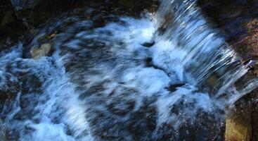 The flow of water in a small waterfall in mountain creek top view photo