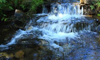 The flow of water in a small waterfall of a rocky stream top view photo