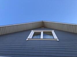 window on the gable of a country house, blue sky, low angle view photo