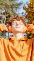 Young person adjusting headphones in autumn forest setting. Relaxation and outdoor activities. photo