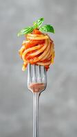 Fork holding spaghetti swirl with rich tomato sauce. Italian cuisine advertising or cooking blogs. photo