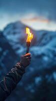 Hand holding torch illuminates mountain landscape at dusk. Symbolizing hope, resilience, and adventure themes. photo