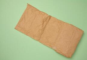Roll of brown wrapping paper on green background, top view photo