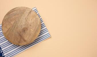 Empty round brown wooden cutting board on a brown background, top view photo