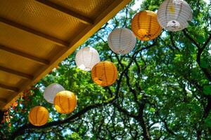 Lanterns are hung under the bridge with a background of sky and green trees photo