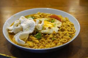 Javanese godok noodles topped with egg, shredded chicken, crackers photo