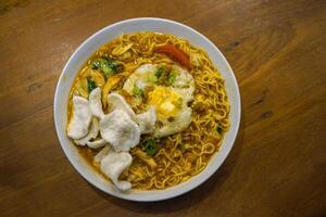 Javanese godok noodles topped with egg, shredded chicken, crackers photo