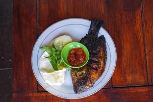 grilled fish with chili sauce and fresh vegetables in the form of cucumber, basil leaves, cabbage leaves photo