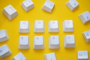 2024 New Year goal, Word GOAL 2024 written on computer keyboard keys isolated on a yellow background. photo