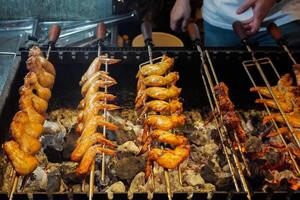 Grilling chicken wings with charcoal that is turned manually by hand photo