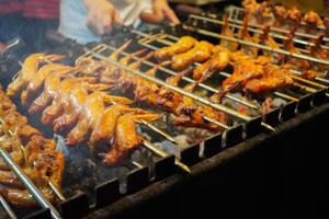 Grilling chicken wings with charcoal that is turned manually by hand photo