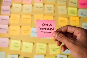 Hand hold sticky notes with words Choose Happiness. Motivational words for personal development, inspirational handwriting. Sticky notes background photo