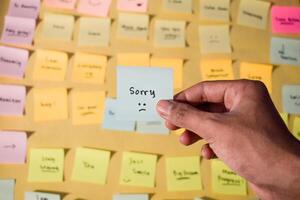 Hand hold sticky notes with words sorry, Motivational for personal development, inspirational handwriting. Sticky notes background photo